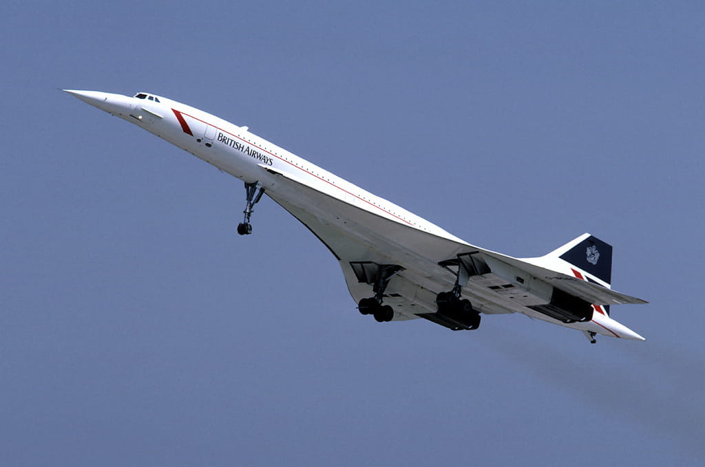 British Airways Concorde taking off, nose up with landing gear down against a clear blue sky