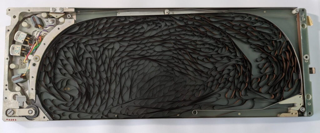 Interior of a hard disk drive with a dense stack of circular platters and left-side electronics visible.