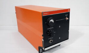 Orange metal test instrument with a black front panel, model 642C-1, featuring a large dial, channel knob, and headphones jack.
