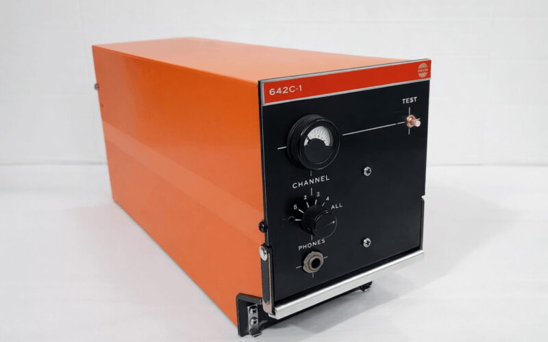 Orange metal test instrument with a black front panel, model 642C-1, featuring a large dial, channel knob, and headphones jack.