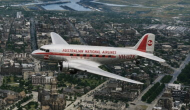 Vintage silver airliner with red stripe reading 'AUSTRALIAN NATIONAL AIRLINES' over a city, registration VH-UZK, early jet era styling with a cathedral visible below.