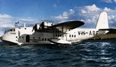 White amphibious transport aircraft on calm water, Qantas Empire Airways Brisbane inscription visible on fuselage, registration C00EE.