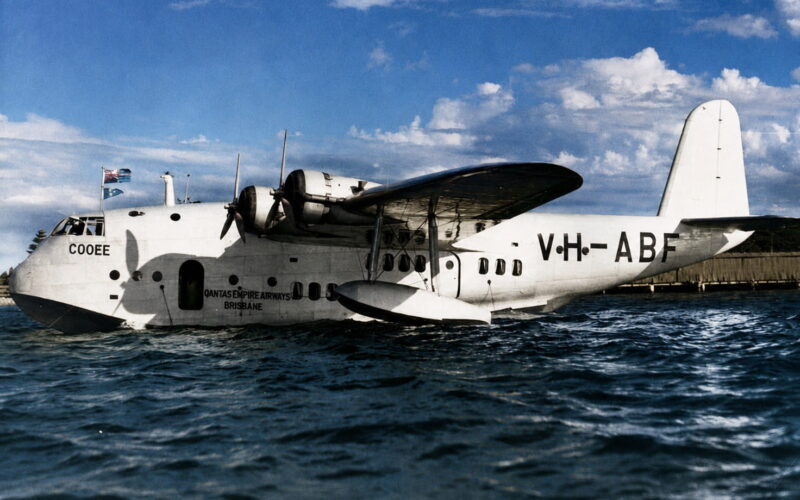 White amphibious transport aircraft on calm water, Qantas Empire Airways Brisbane inscription visible on fuselage, registration C00EE.