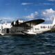 White amphibious transport aircraft on calm water, Qantas Empire Airways Brisbane inscription visible on fuselage, registration C00EE.